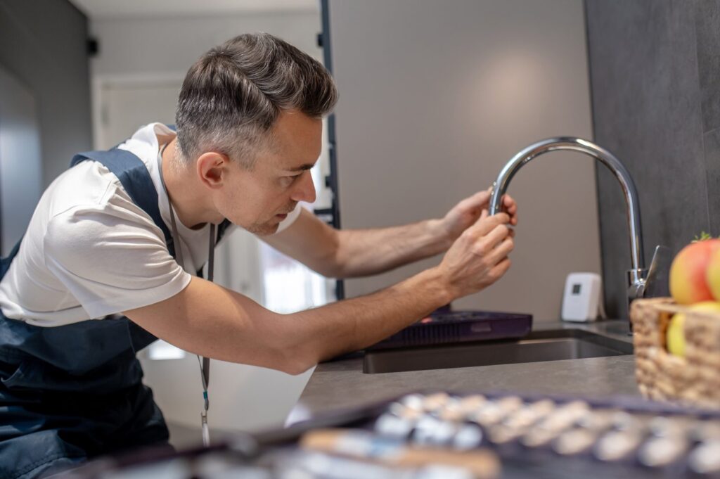 Techniker prüft Wasserhahn vor Probenahme zur Legionellenprüfung